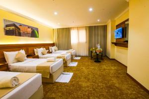 a hotel room with four beds and a flat screen tv at Bab ALMultazam Concorde Hotel in Mecca