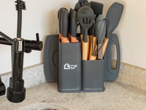 a black container filled with utensils on a counter at Loft Alegria in Avaré +9 photos