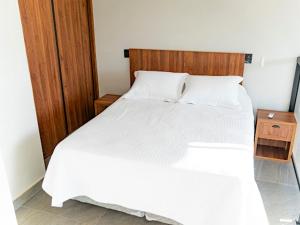 a bedroom with a white bed with a wooden headboard at Loft Alegria in Avaré