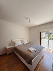 a white bedroom with a large bed and a window at Descanso, Mar & Conforto in Esposende