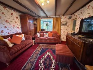 a living room with couches and a flat screen tv at Shop Cottage, Findhorn in Findhorn