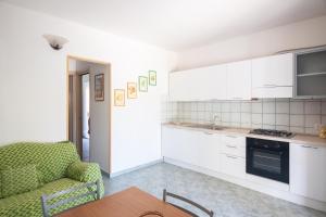 a kitchen with white cabinets and a couch and a table at Trilocale - Via Pisa in San Teodoro