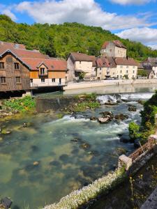 a river in a town with houses and a bridge at La maison de la Loue in Lods
