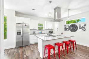 a kitchen with white cabinets and red bar stools at The Ultimate View House in Dallas +14 photos