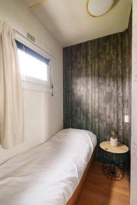 a small bedroom with a bed and a window at Knus houten huisje bij het bos in Anloo +28 photos
