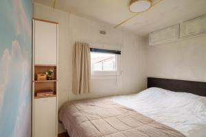 a small bedroom with a bed and a window at Knus houten huisje bij het bos in Anloo