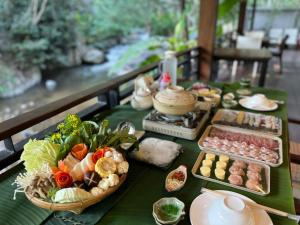 a green table topped with food and bowls of food at The ForRest Peace Forest แม่กำปอง in Ban Huai Kaeo
