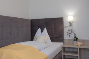 a bedroom with a large bed with a yellow blanket at Hotel Drescher in Mörbisch am See