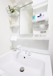 a white bathroom with a sink and a mirror at たびあかりn in Nishi-nakasange +20 photos