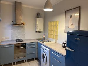 a kitchen with blue cabinets and a washing machine at Jurmala Cozy Vibes - self check in in Jūrmala