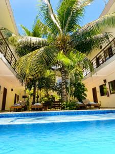 a swimming pool with a palm tree and tables at Hotel Céntrico Tulum in Tulum