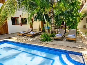 a swimming pool with chaises and chairs next to a house at Hotel Céntrico Tulum in Tulum