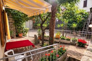 a patio with a red table and umbrella and flowers at Casa Giovio - Romantico appartamento di montagna in Blessagno
