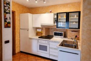 a kitchen with white cabinets and a sink and a refrigerator at Casa Giovio - Romantico appartamento di montagna in Blessagno +8 photos