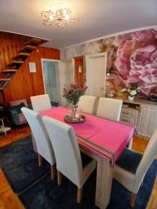 a dining room with a pink table and white chairs at Rózsa nyaralóház in Balatonboglár