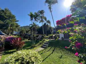 a garden with palm trees and flowers in front of a house at Blue Privacy Resort in Nathon Bay