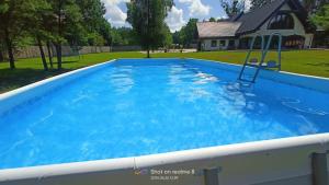 a large blue swimming pool with a slide in a yard at Dworek Willa Biała Góra in Biała Góra