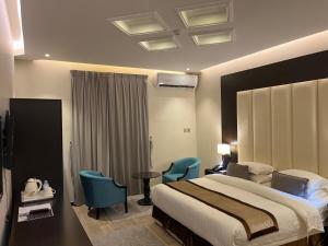 a hotel room with a bed and two blue chairs at Address Sharurah Hotel in Sharurah +43 photos