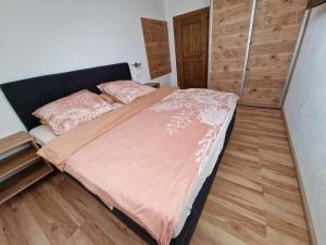 a bedroom with a bed with pink sheets and wooden floors at Ferienwohnung Silvia in Sankt Kanzian