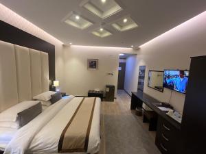 a bedroom with a large bed and a flat screen tv at Address Sharurah Hotel in Sharurah