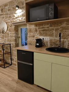 a kitchen with a counter with a sink and a microwave at Maison Jolie in Vlachopoulátika