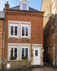 a brick building with two windows and a white door at La fa'Meuse escale in Vireux-Wallerand