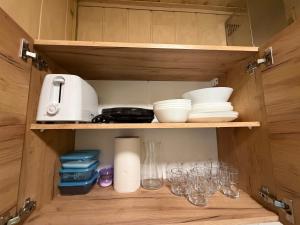a cupboard with some dishes and glasses on it at ApartmentsByMatyrafa-XVI in Tarnowskie Góry +3 photos