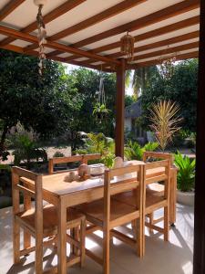 a wooden table and chairs under a wooden pergola at SA Oeona Bungalow in Nembrala