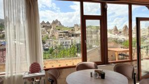 a room with a table and chairs and large windows at Nature Park Cave Hotel in Göreme