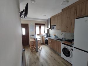 a kitchen with wooden cabinets and a white refrigerator at Villa Playa del Silencio in Castañeras