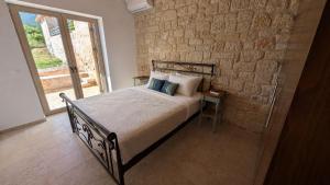 a bedroom with a bed and a brick wall at Achilles Cottage in Kardamyli +14 photos