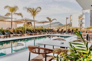 a hotel pool with tables and chairs and palm trees at Monun Hotel in Ksamil