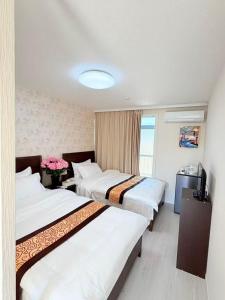 ein Hotelzimmer mit drei Betten und einem Fernseher in der Unterkunft MUTSUMI Hotel in Saga