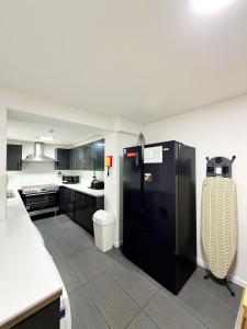 a large kitchen with a black refrigerator in it at Britlodge Ruskin Stay in Manchester +44 photos