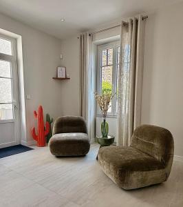 a living room with two chairs and a ottoman at GIte de la Grande Plage in Pléneuf-Val-André