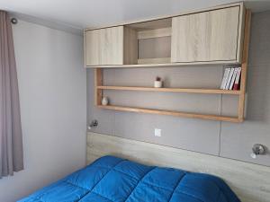 a bedroom with a blue bed and a cabinet at Sous les Pins dans camping 4 étoiles MH familial 322 6 à 8 couchages 2 salles de bain 2 WC in Saint-Julien-en-Born +33 photos