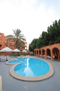 a large swimming pool in a resort with chairs and umbrellas at Settle inn Fajr Boutique hotel in Cairo
