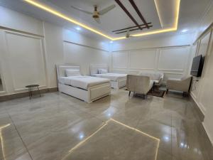 a room with two beds and a tv and chairs at Pc Inn Executive Class Hotel in Sukkur