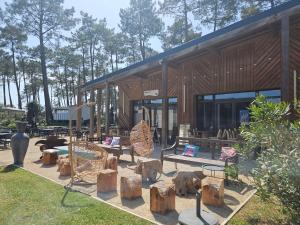 a building with chairs and logs in front of it at Sous les Pins dans camping 4 étoiles MH familial 322 6 à 8 couchages 2 salles de bain 2 WC in Saint-Julien-en-Born