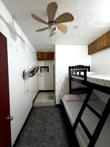 a room with a bunk bed and a ceiling fan at Villaroman Inn in Baler