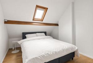 a bedroom with a bed with white sheets and a window at Oyster Loft Ostend in Ostend