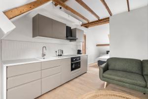 a kitchen with white cabinets and a green chair at Oyster Loft Ostend in Ostend