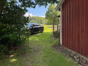 a car parked in a yard next to a red barn at Haqvins stuga in Förslöv