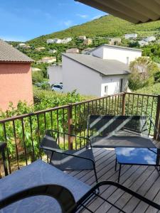 a patio with two chairs and a table on a balcony at Soleil, Piscine, Parking et Bienvenue à Sisco in Sisco