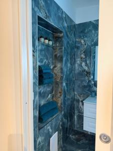 a bathroom with a blue tiled shower with blue towels at B&B Aura in Pontecagnano