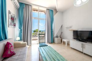 a living room with a large window and a television at Saranda Hotel in Sarandë