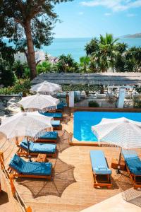 a group of chairs and umbrellas next to a swimming pool at Saranda Hotel in Sarandë
