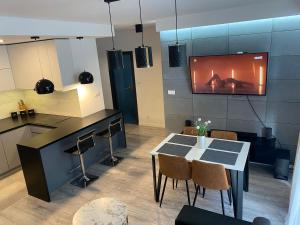 a kitchen with a table and a tv on the wall at Apartament AquaTower, Aquapark Reda in Reda