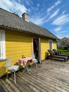 a yellow house with a table and chairs on a deck at Posti Tiny House with Garden in Haapsalu