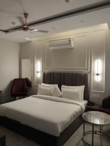 a bedroom with a large white bed and two chairs at Leaf 9 Imperial, Subhash Nagar, Pacific Mall in New Delhi